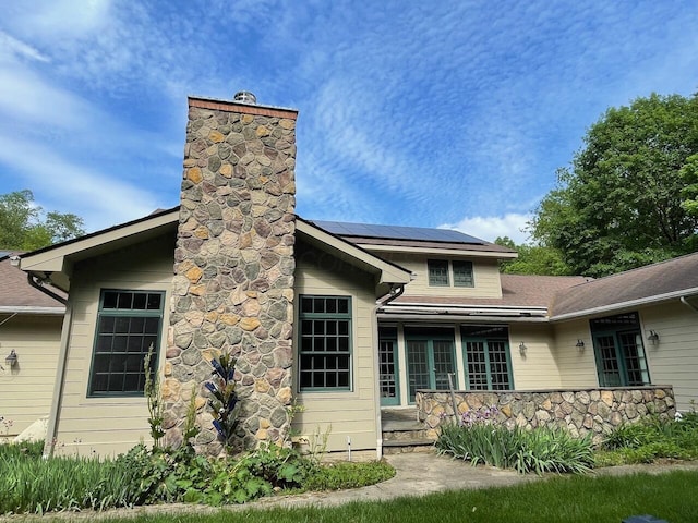 61 Wyddfa Ct, Granville, OH 43023 - back of property with roof mounted solar panels, a chimney, stone siding, and a deck