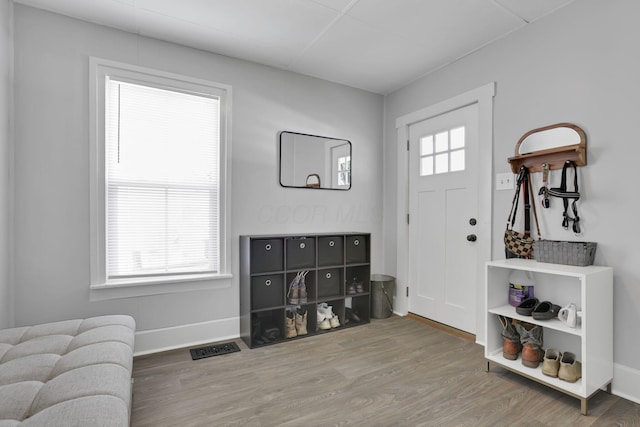 foyer with baseboards, visible vents, and wood finished floors