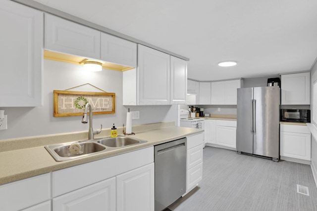 kitchen with a sink, stainless steel appliances, white cabinetry, and light countertops