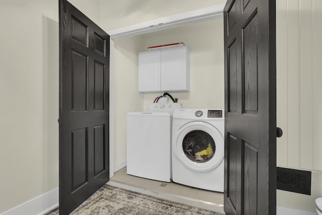 washroom featuring separate washer and dryer, cabinet space, and baseboards