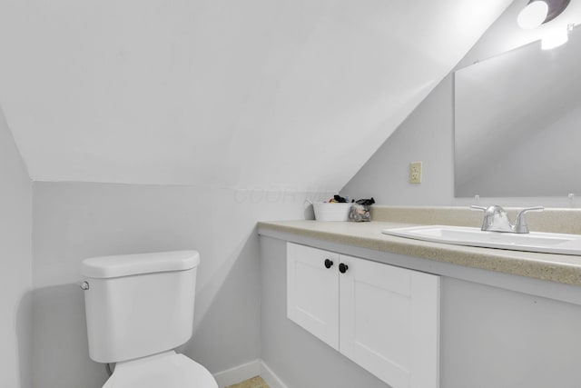 bathroom with vanity, baseboards, toilet, and lofted ceiling
