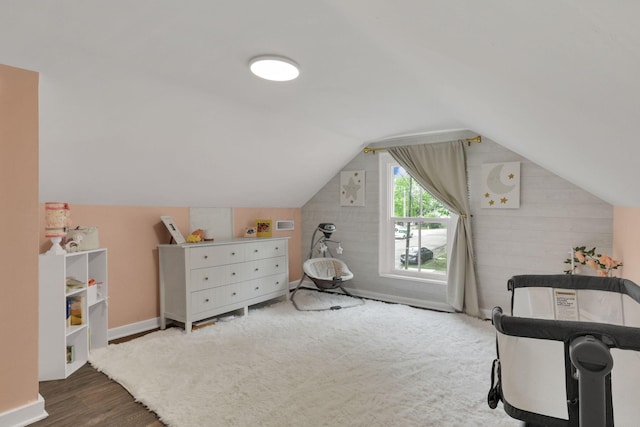interior space with vaulted ceiling, wooden walls, and wood finished floors