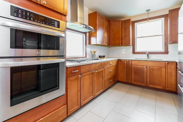 24 Brighton Rd, Columbus, OH 43202 - kitchen featuring wall chimney range hood, a sink, appliances with stainless steel finishes, brown cabinetry, and backsplash