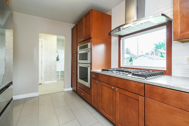 24 Brighton Rd, Columbus, OH 43202 - kitchen featuring wall chimney exhaust hood, stainless steel appliances, brown cabinetry, baseboards, and light stone counters