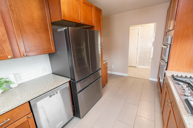 24 Brighton Rd, Columbus, OH 43202 - kitchen featuring appliances with stainless steel finishes, brown cabinets, baseboards, decorative backsplash, and light stone counters