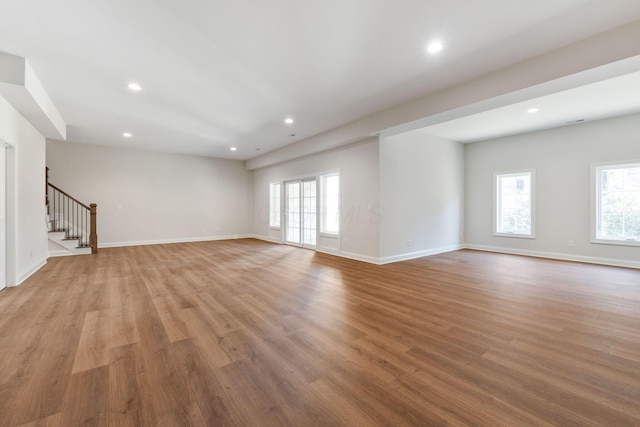 1473 Dogwood Loop, Powell, OH 43065 - unfurnished living room featuring stairs, plenty of natural light, light wood-type flooring, and recessed lighting