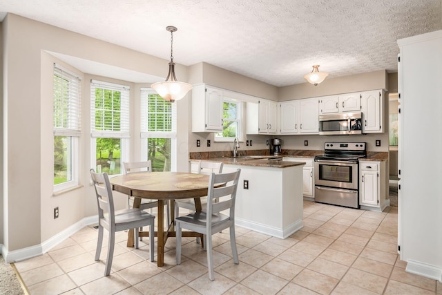 kitchen featuring appliances with stainless steel finishes, white cabinets, a textured ceiling, and light tile patterned floors