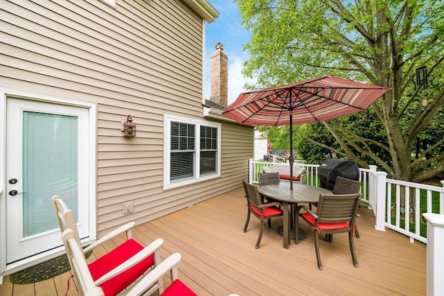 wooden deck with outdoor dining space and area for grilling