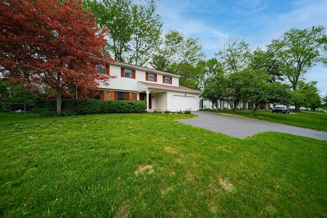 traditional-style home featuring driveway, a front yard, and a garage
