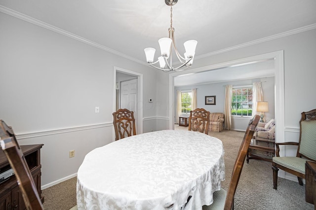 dining room featuring a chandelier, light colored carpet, ornamental molding, and baseboards