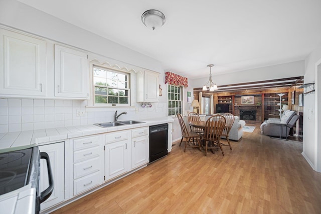 kitchen featuring black dishwasher, stove, tile counters, a sink, and white cabinets