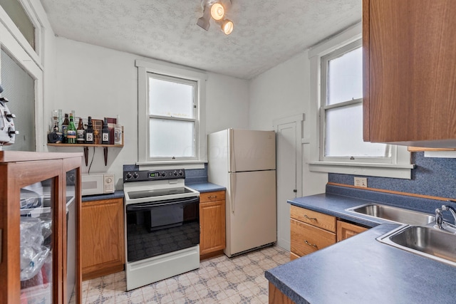 1205 Bryden Rd Unit 7, Columbus, OH 43205 - kitchen featuring white appliances, light floors, a textured ceiling, dark countertops, and a sink