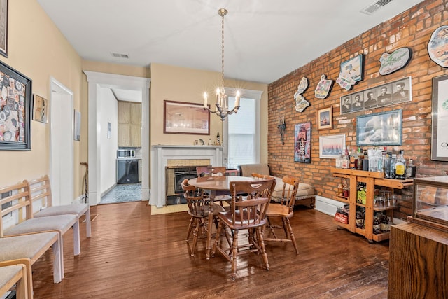 1205 Bryden Rd Unit 7, Columbus, OH 43205 - dining room featuring brick wall, a chandelier, hardwood / wood-style floors, baseboards, and a fireplace