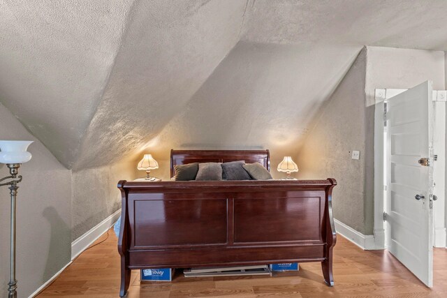 1205 Bryden Rd Unit 7, Columbus, OH 43205 - bedroom with lofted ceiling, a textured wall, wood finished floors, a textured ceiling, and baseboards