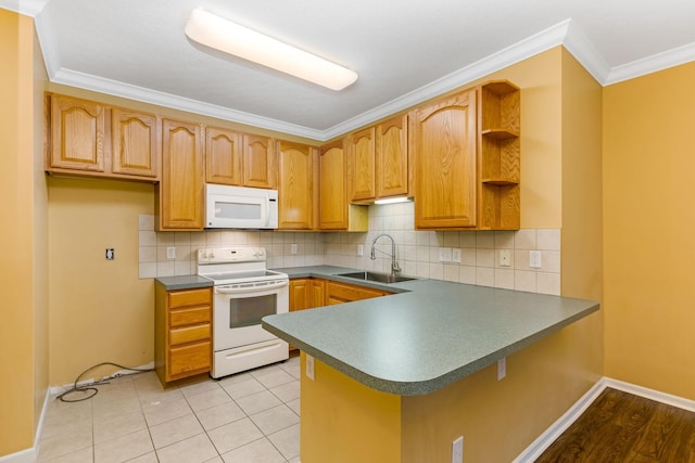 kitchen featuring white appliances, a sink, dark countertops, a peninsula, and crown molding
