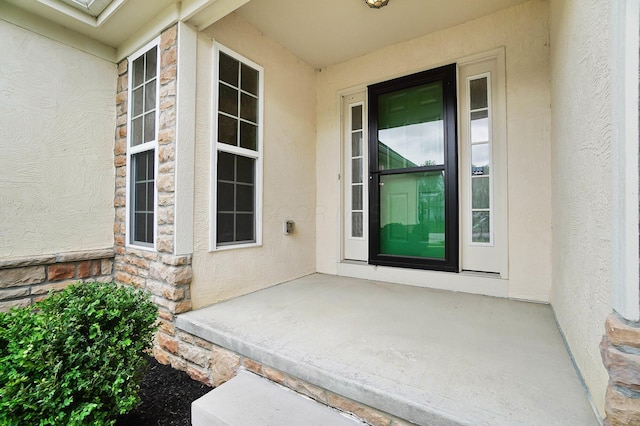 view of exterior entry featuring stucco siding and stone siding