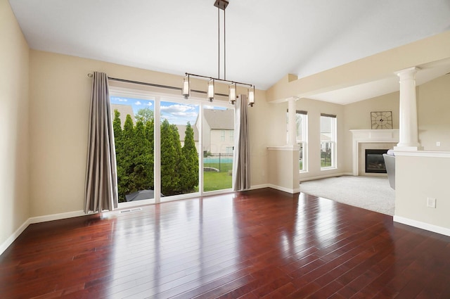 unfurnished living room featuring a glass covered fireplace, lofted ceiling, ornate columns, wood finished floors, and baseboards