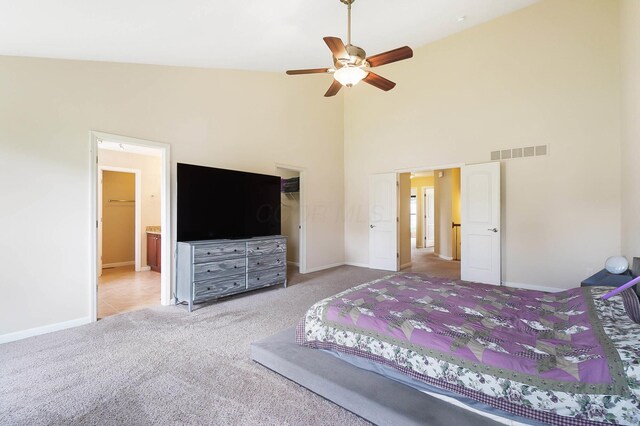 carpeted bedroom with baseboards, a towering ceiling, connected bathroom, a closet, and a ceiling fan