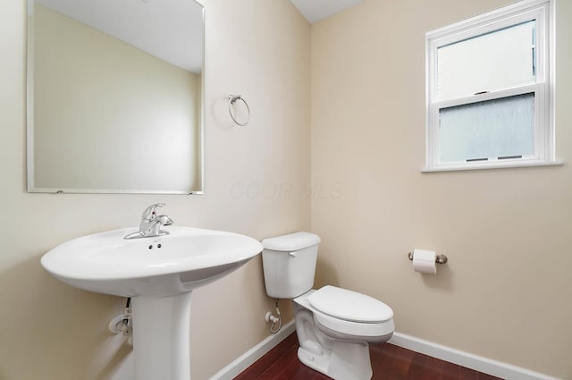 bathroom with baseboards, toilet, and wood finished floors