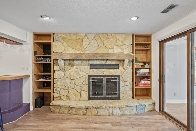 2825 Kings Corners Rd E, Mansfield, OH 44904 - unfurnished living room featuring wood finished floors, a stone fireplace, a textured ceiling, and built in features
