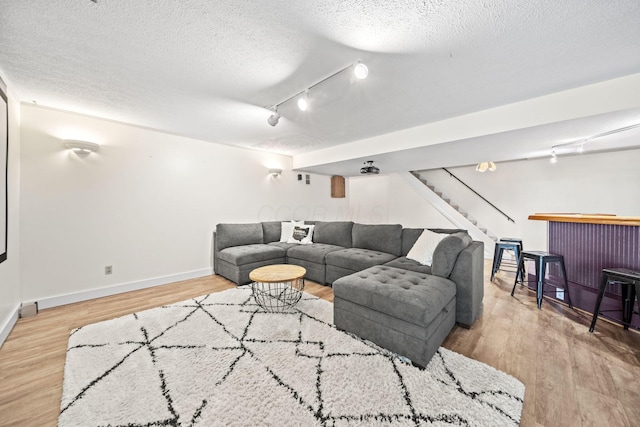 2825 Kings Corners Rd E, Mansfield, OH 44904 - living room with rail lighting, stairs, a textured ceiling, wood finished floors, and baseboards