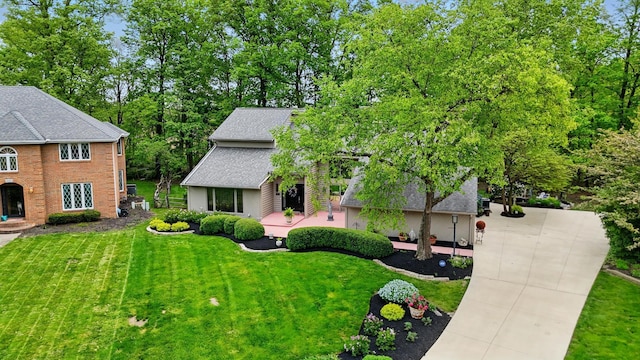 view of front of home featuring a front lawn, driveway, and a shingled roof