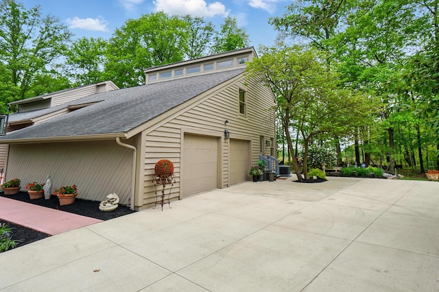 view of home's exterior with a shingled roof, driveway, and an attached garage