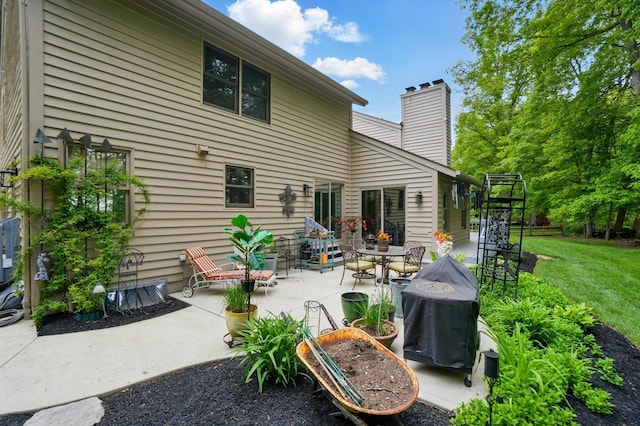 rear view of house featuring a patio, a chimney, and a yard