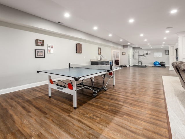 rec room featuring wood finished floors, recessed lighting, baseboards, and wet bar