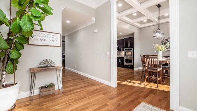 hall featuring ornamental molding, coffered ceiling, light wood-style floors, beamed ceiling, and baseboards