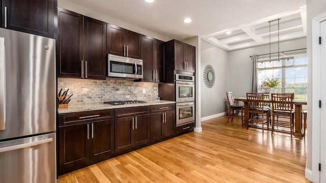 kitchen featuring appliances with stainless steel finishes, baseboards, light wood-style floors, backsplash, and coffered ceiling