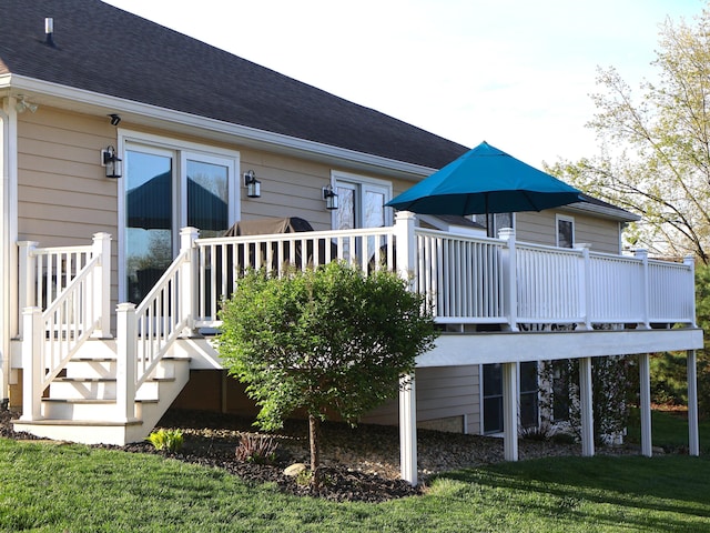 rear view of property featuring a wooden deck, roof with shingles, and a yard