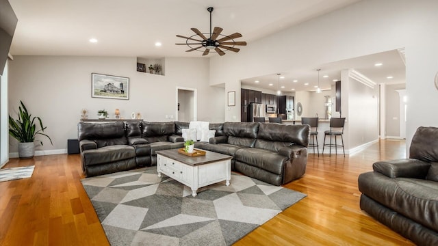 living area with a ceiling fan, recessed lighting, light wood finished floors, vaulted ceiling, and baseboards