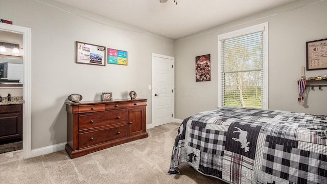 bedroom with light colored carpet, baseboards, and ensuite bathroom