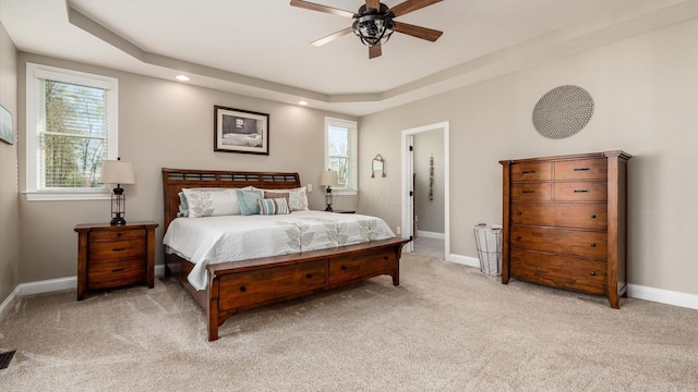 bedroom featuring light colored carpet, baseboards, a raised ceiling, recessed lighting, and a ceiling fan
