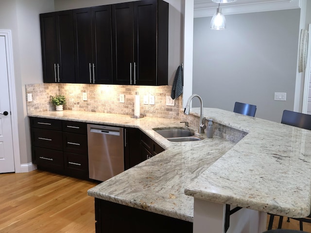 kitchen with stainless steel dishwasher, a sink, a peninsula, ornamental molding, and tasteful backsplash