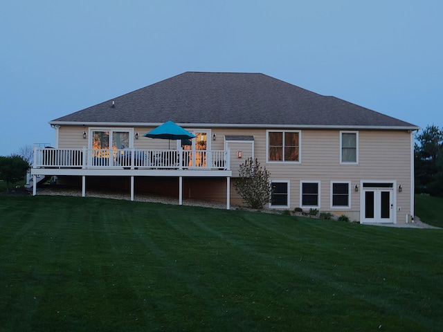 rear view of property featuring a deck, a lawn, and french doors