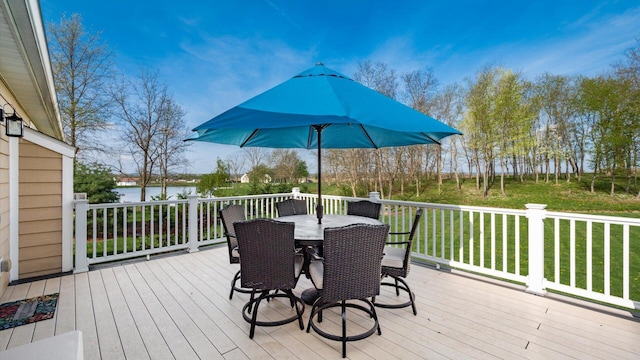 deck featuring a water view, outdoor dining area, and a yard