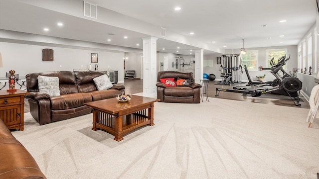 living area featuring recessed lighting, ornate columns, and light colored carpet