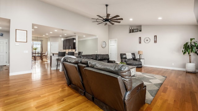 living area with vaulted ceiling, ceiling fan, light wood-type flooring, baseboards, and recessed lighting