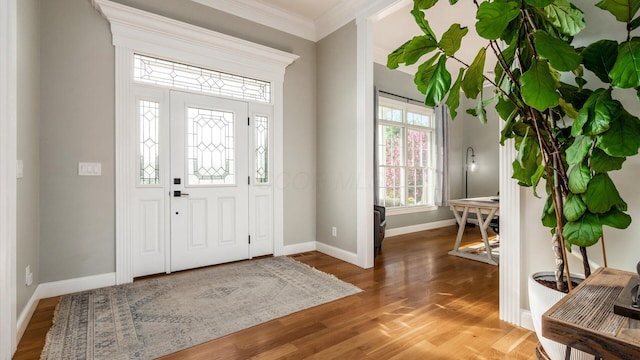 foyer featuring baseboards, crown molding, and wood finished floors