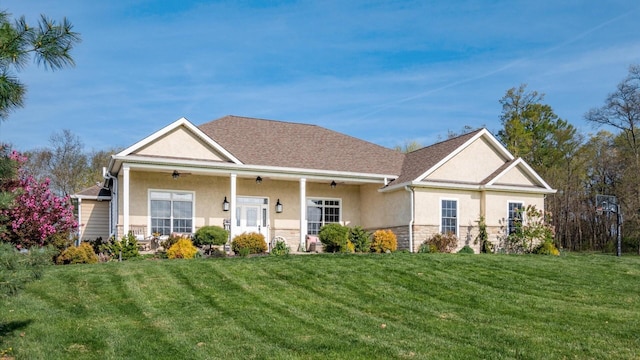 view of front of property with ceiling fan, stucco siding, a front lawn, and stone siding