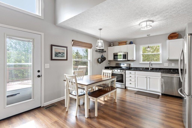 3102 Menzola Dr, Columbus, OH 43228 - kitchen with stainless steel appliances, a sink, dark countertops, white cabinets, and dark wood finished floors