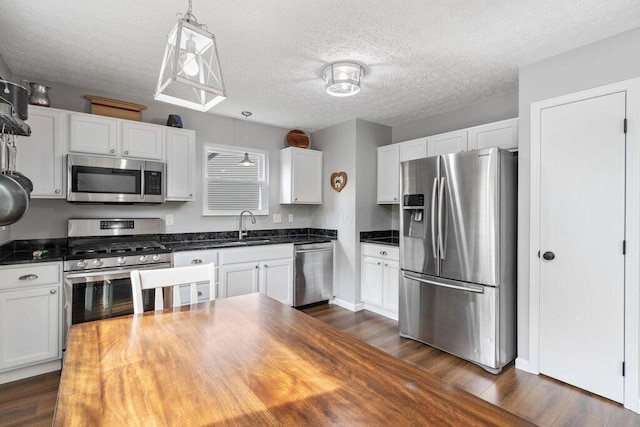 3102 Menzola Dr, Columbus, OH 43228 - kitchen with stainless steel appliances, dark wood-type flooring, a sink, white cabinets, and pendant lighting