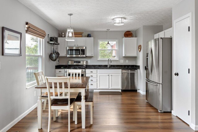 3102 Menzola Dr, Columbus, OH 43228 - kitchen with appliances with stainless steel finishes, white cabinetry, dark countertops, dark wood-style floors, and a textured ceiling