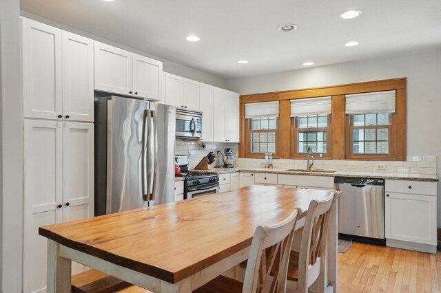 kitchen with stainless steel appliances, a sink, decorative backsplash, white cabinetry, and recessed lighting
