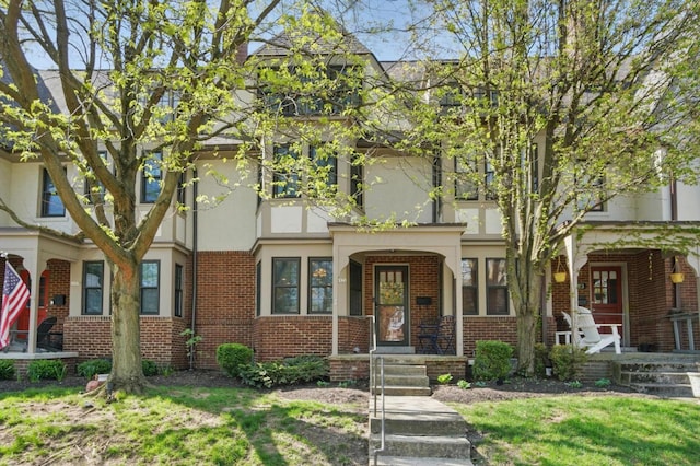 view of property featuring stucco siding, brick siding, and covered porch