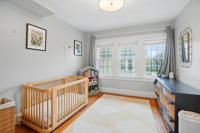 bedroom with wood finished floors and a nursery area