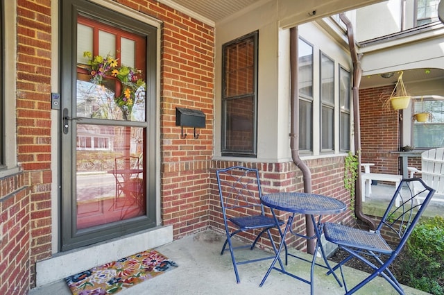 property entrance with brick siding and a porch