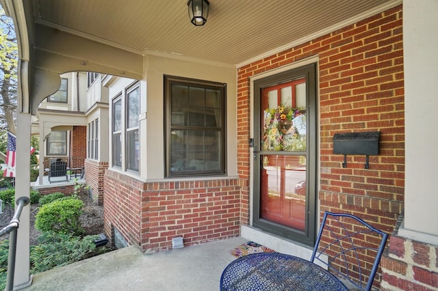 doorway to property with brick siding and covered porch